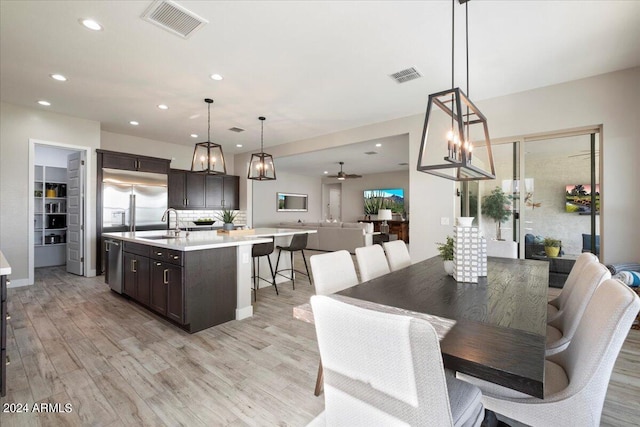 dining area with ceiling fan, sink, and light wood-type flooring