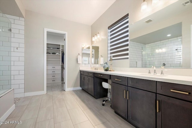 bathroom featuring tiled shower and vanity