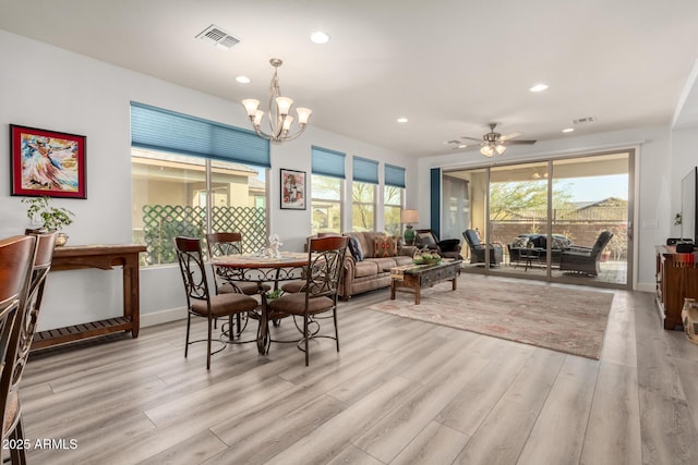 dining space featuring ceiling fan with notable chandelier and light wood-type flooring