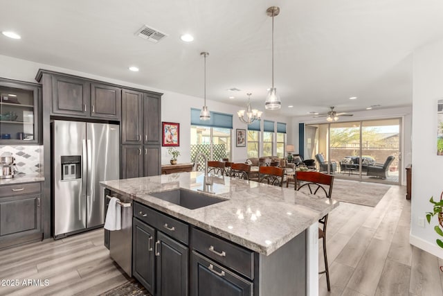 kitchen featuring appliances with stainless steel finishes, a breakfast bar, sink, a kitchen island with sink, and light wood-type flooring