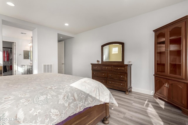 bedroom with a walk in closet, light hardwood / wood-style floors, and a closet