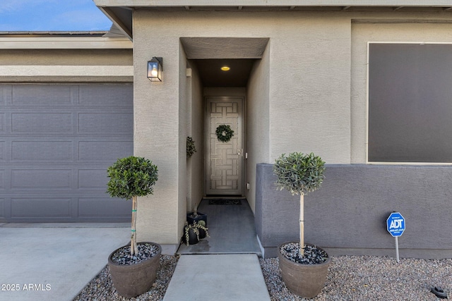 doorway to property featuring a garage and stucco siding