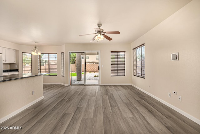1655 W Stanford Ave, Gilbert, AZ 85233 - unfurnished living room featuring baseboards, dark wood finished floors, ceiling fan, and a chandelier