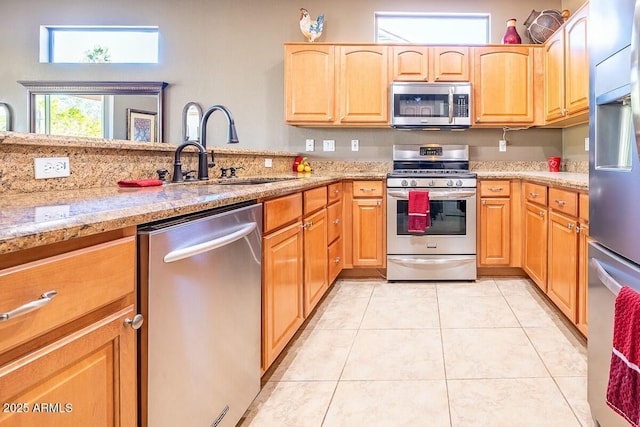 kitchen with light stone countertops, sink, light tile patterned floors, and stainless steel appliances