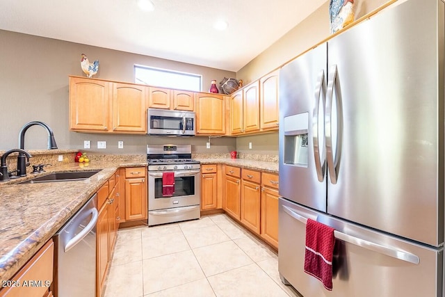 kitchen featuring light stone counters, sink, light tile patterned floors, and appliances with stainless steel finishes