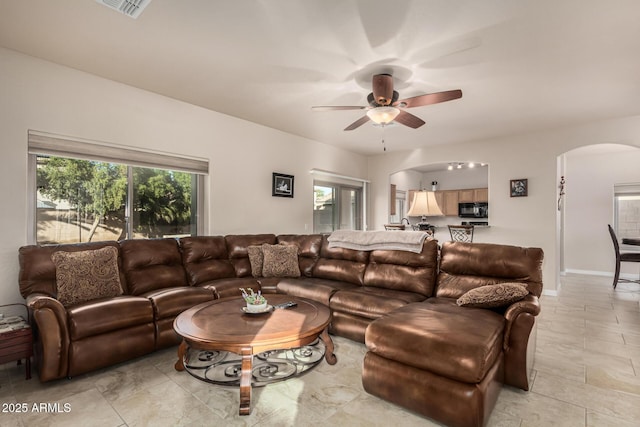 living area featuring arched walkways, ceiling fan, and baseboards