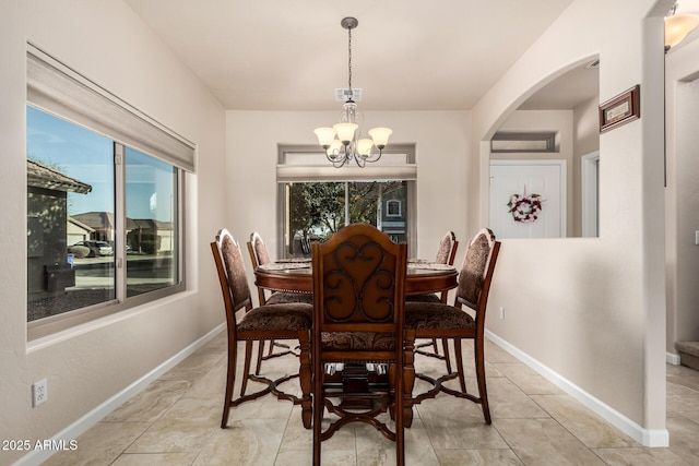 dining space featuring baseboards, arched walkways, visible vents, and a notable chandelier