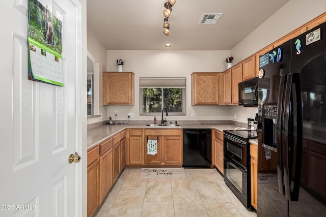 kitchen with visible vents, brown cabinets, light countertops, black appliances, and a sink