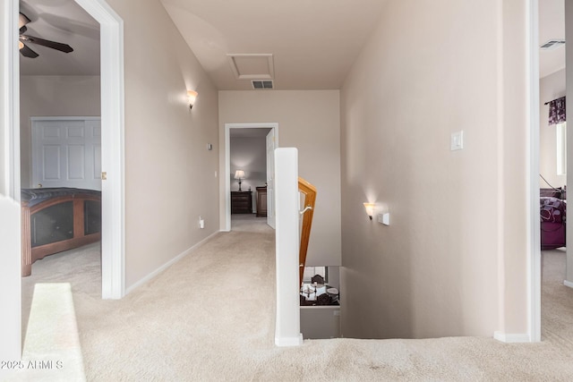 corridor with carpet floors, an upstairs landing, visible vents, and attic access