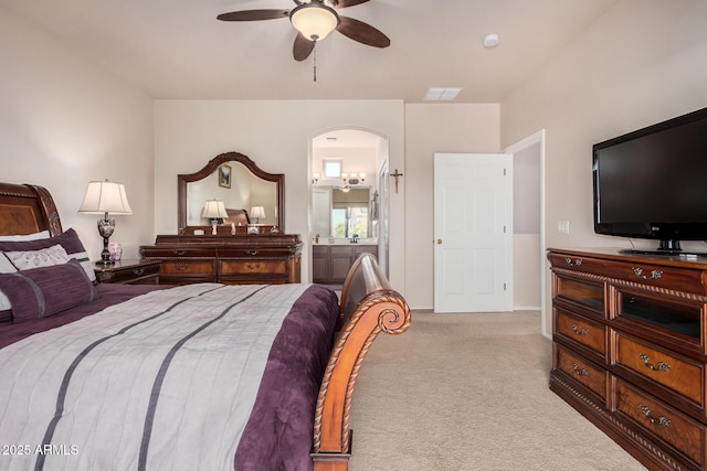 carpeted bedroom with a ceiling fan, arched walkways, visible vents, and ensuite bathroom