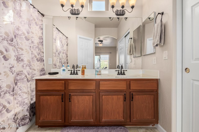 bathroom with ceiling fan with notable chandelier, a sink, a shower with shower curtain, and double vanity