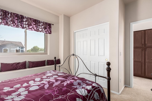 bedroom with baseboards, a closet, and light colored carpet