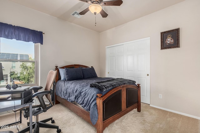 bedroom with a closet, visible vents, light carpet, ceiling fan, and baseboards