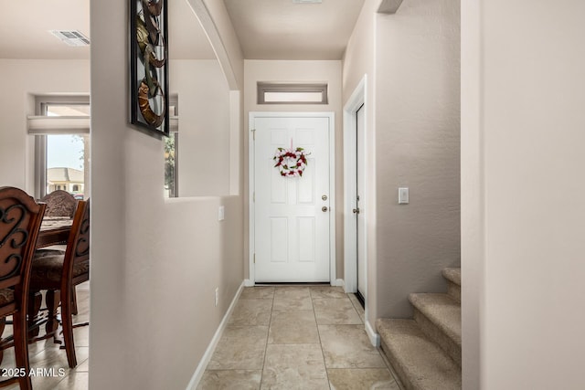 doorway to outside featuring arched walkways, visible vents, baseboards, and light tile patterned floors