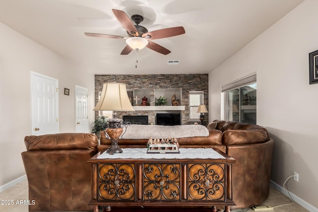 living room featuring light tile patterned floors, ceiling fan, a fireplace, visible vents, and baseboards