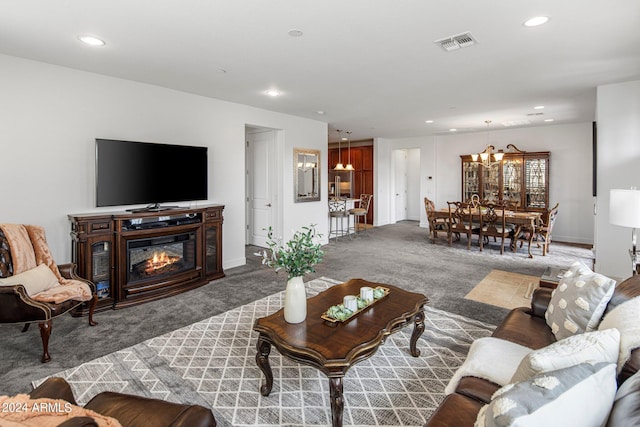 carpeted living room with an inviting chandelier