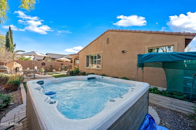 view of pool with fence and a hot tub