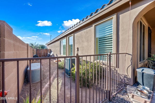 view of property exterior with fence, a tiled roof, and stucco siding