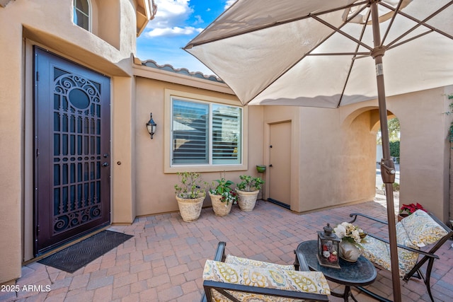 doorway to property featuring a patio area, a tiled roof, and stucco siding