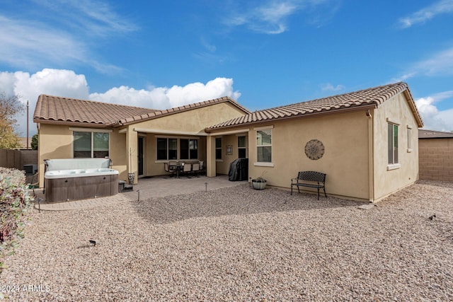 back of property with central air condition unit, a patio, and a hot tub