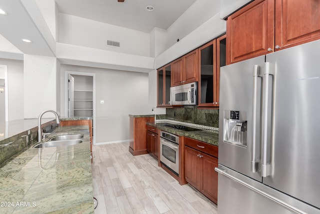 kitchen featuring light stone countertops, light wood-type flooring, sink, and appliances with stainless steel finishes