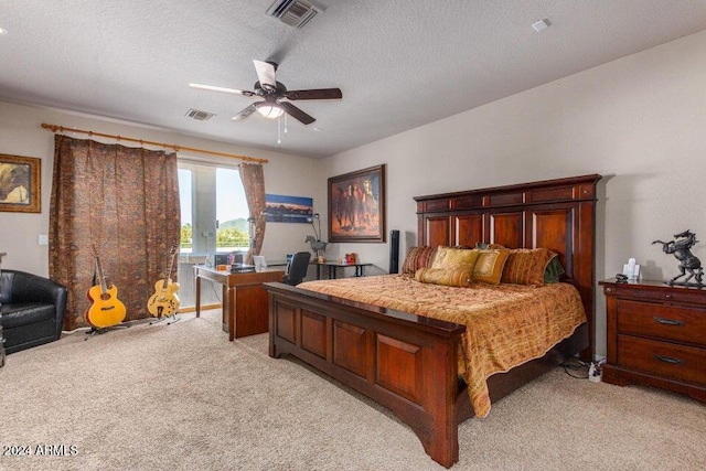 bedroom with a textured ceiling, light colored carpet, and ceiling fan