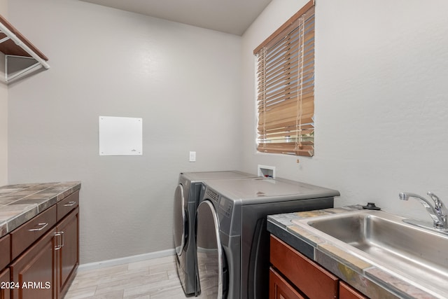 laundry room with light hardwood / wood-style floors, cabinets, independent washer and dryer, and sink