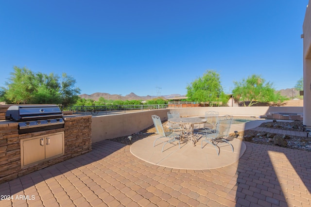 view of patio with a mountain view, an outdoor kitchen, a fenced in pool, and grilling area