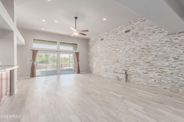 unfurnished living room featuring ceiling fan, a towering ceiling, and light hardwood / wood-style floors