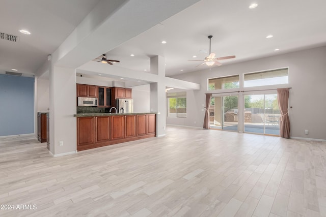 kitchen with ceiling fan, tasteful backsplash, appliances with stainless steel finishes, and light hardwood / wood-style flooring