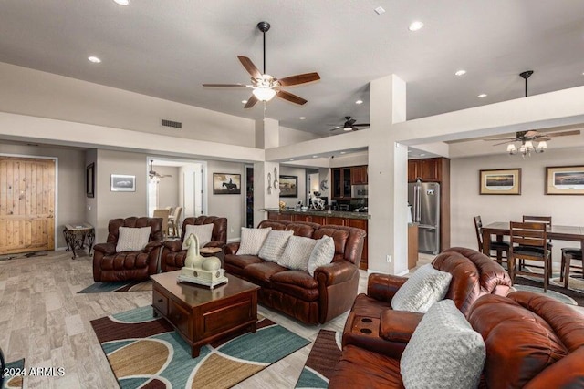 living room with ceiling fan, light hardwood / wood-style floors, and a high ceiling