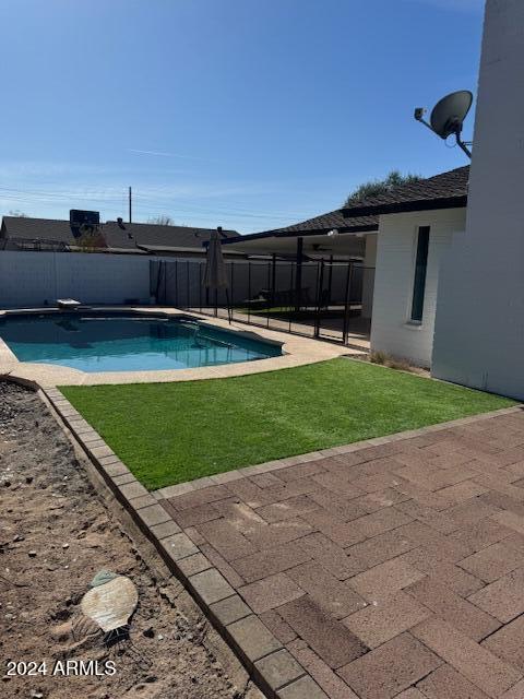 view of pool featuring a diving board, a patio area, and a lawn