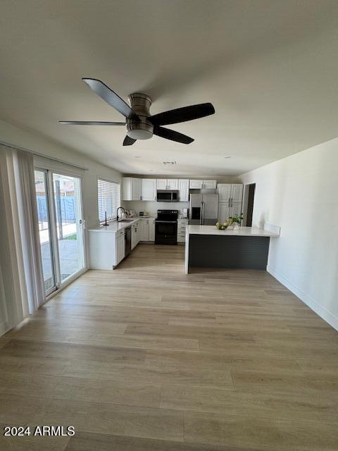 kitchen featuring kitchen peninsula, appliances with stainless steel finishes, ceiling fan, light hardwood / wood-style flooring, and white cabinetry