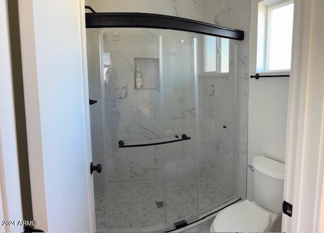 bathroom featuring toilet and an enclosed shower