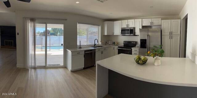 kitchen with appliances with stainless steel finishes, ceiling fan, sink, light hardwood / wood-style flooring, and white cabinetry