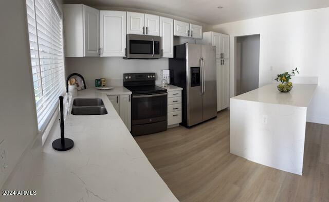 kitchen featuring white cabinetry, sink, light hardwood / wood-style flooring, and appliances with stainless steel finishes