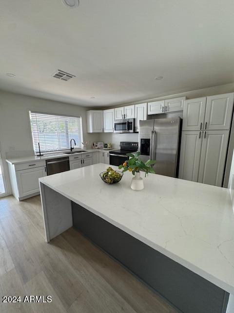 kitchen with white cabinets, sink, light stone counters, and black appliances