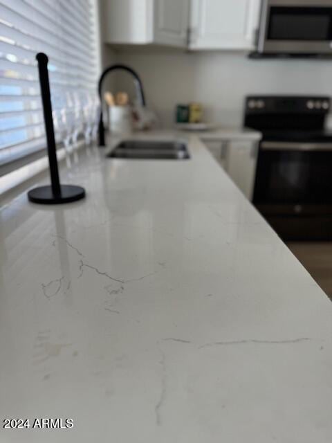 details featuring black stove, white cabinets, and sink