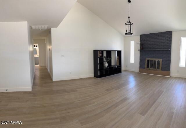 unfurnished living room with wood-type flooring, high vaulted ceiling, and a brick fireplace