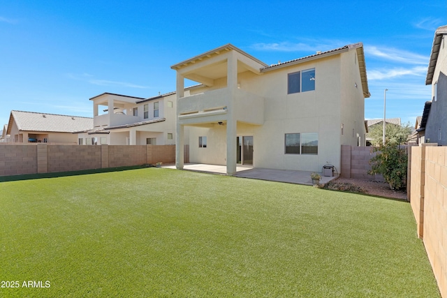 rear view of property featuring a yard, a balcony, and a patio area