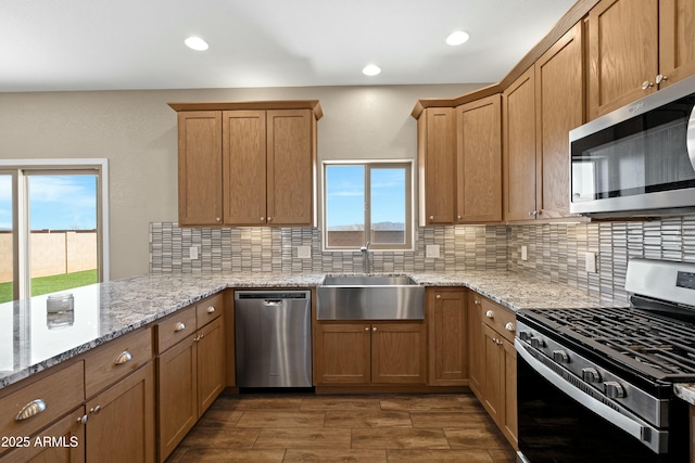 kitchen featuring backsplash, light stone countertops, sink, and appliances with stainless steel finishes