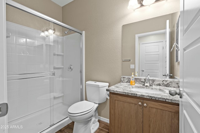 bathroom with vanity, hardwood / wood-style flooring, toilet, and a shower with door