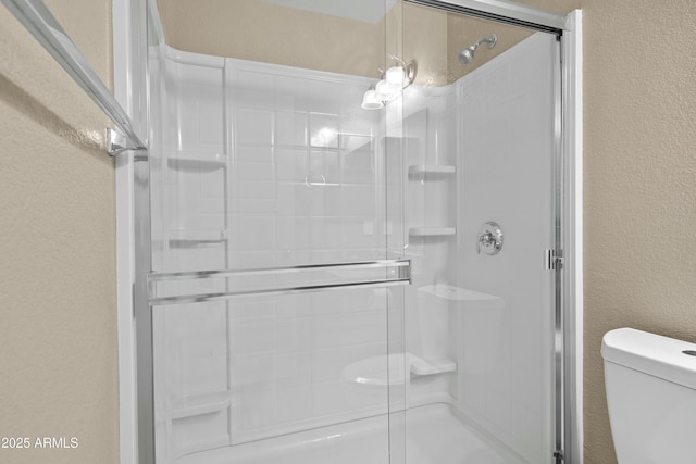 bathroom with toilet and an enclosed shower