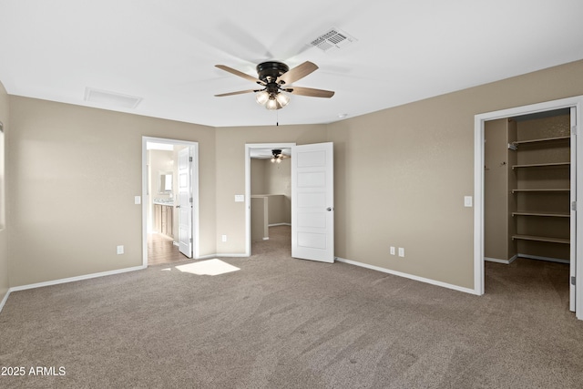 unfurnished bedroom featuring carpet flooring, a spacious closet, a closet, and ceiling fan