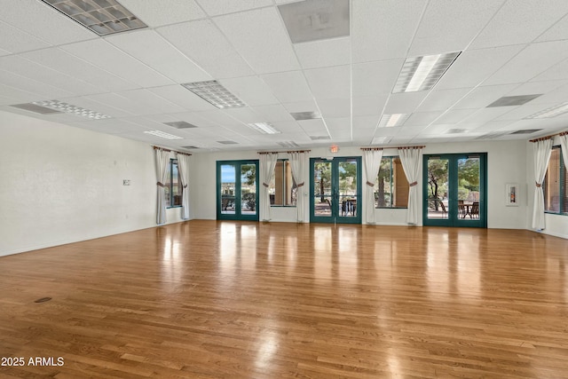 exercise area featuring french doors, a paneled ceiling, and wood-type flooring