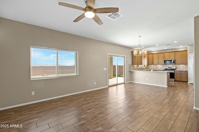 unfurnished living room featuring ceiling fan with notable chandelier