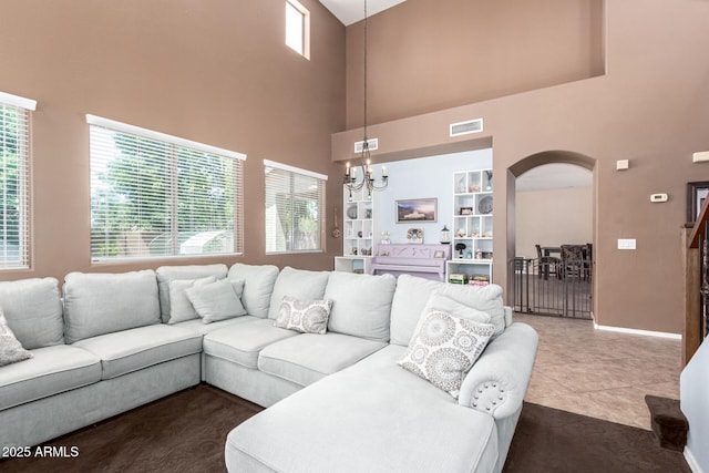 42160 W Arvada Ct, Maricopa, AZ 85138 - tiled living room featuring arched walkways, a towering ceiling, a chandelier, baseboards, and carpet floors