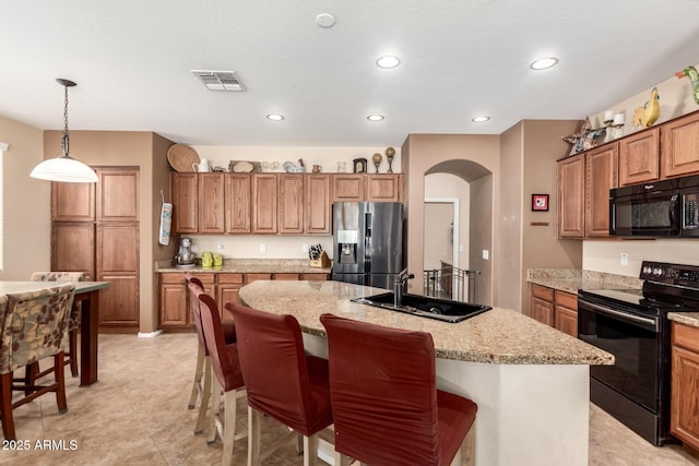 42160 W Arvada Ct, Maricopa, AZ 85138 - kitchen featuring black appliances, a sink, arched walkways, brown cabinets, and a kitchen island