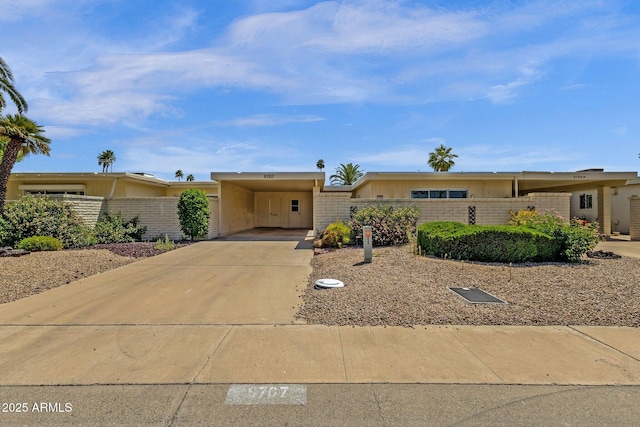 ranch-style house with fence, concrete driveway, and an attached carport
