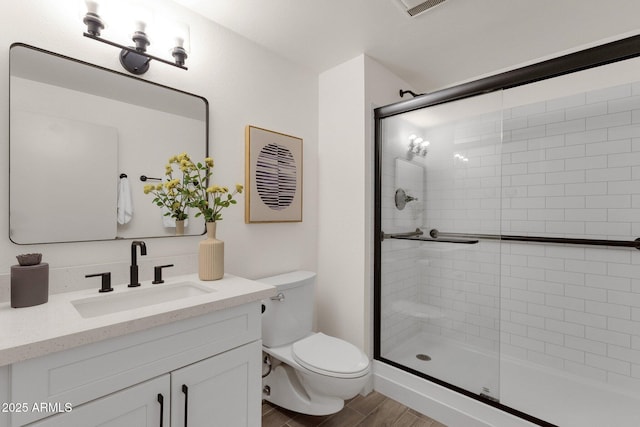 bathroom featuring vanity, wood finished floors, toilet, and a stall shower
